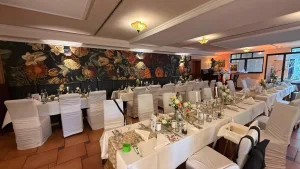 Hochzeitlich eingedecktes Restaurant im Waldhotel Rheinbach am frühen Abend, ohne Gäste, mit dekorierten Tischen.