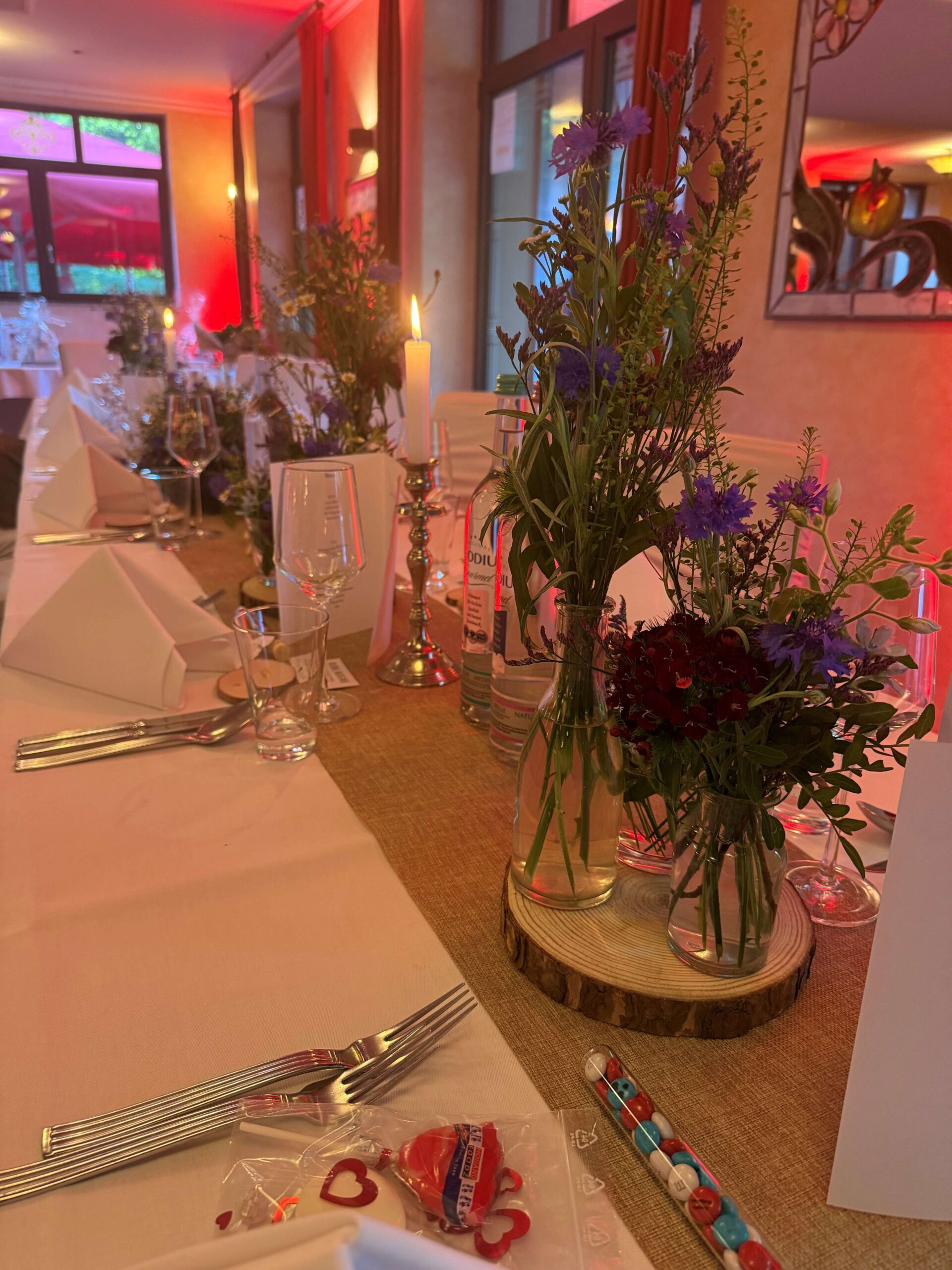 Dekorierter Hochzeitstisch im Waldhotel Rheinbach mit Blumenarrangements von der Blumenbotschaft Vier Jahreszeiten, Kerzen und elegantem Besteck.
