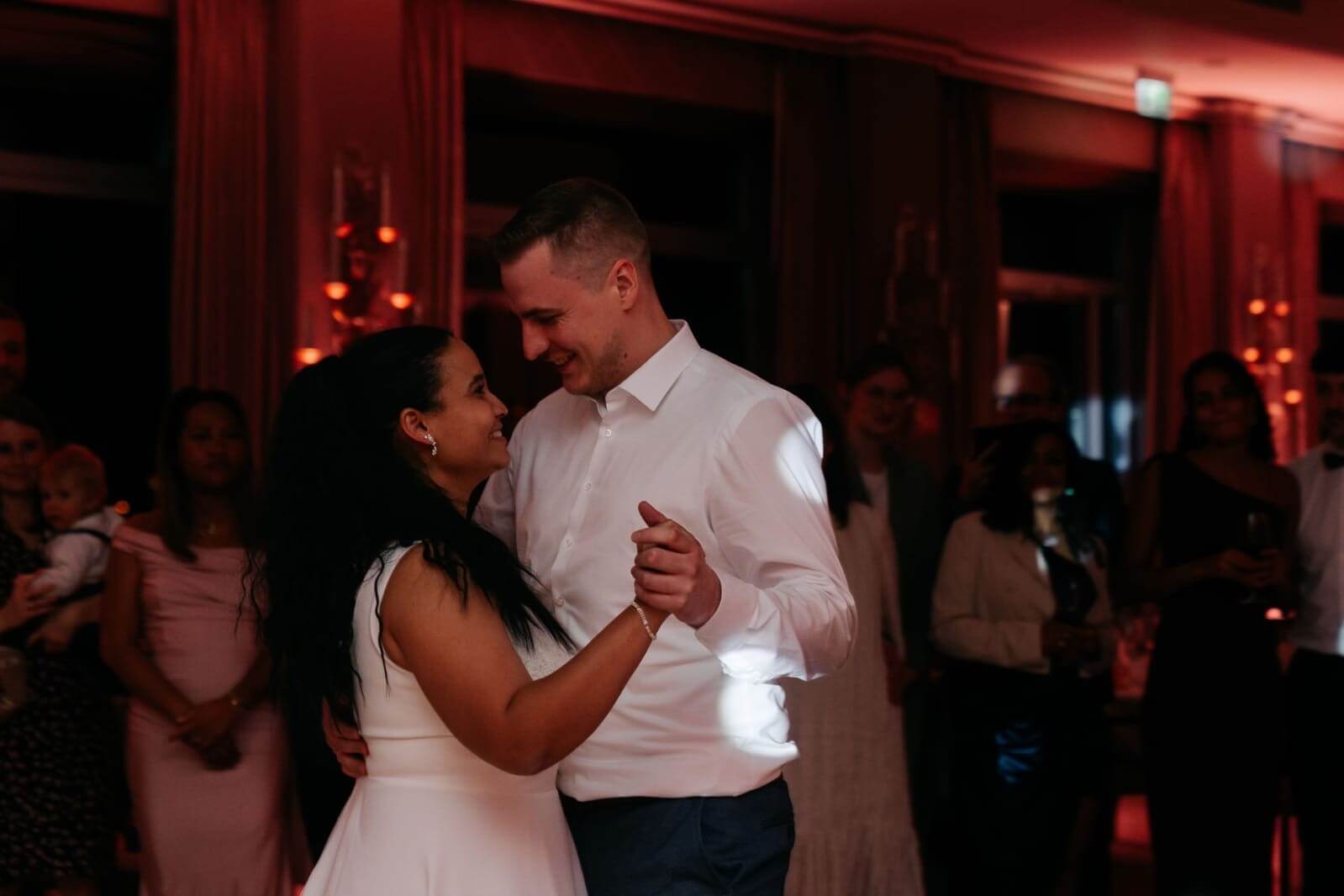 Brautpaar beim Hochzeitstanz mit Gästen im Hintergrund
