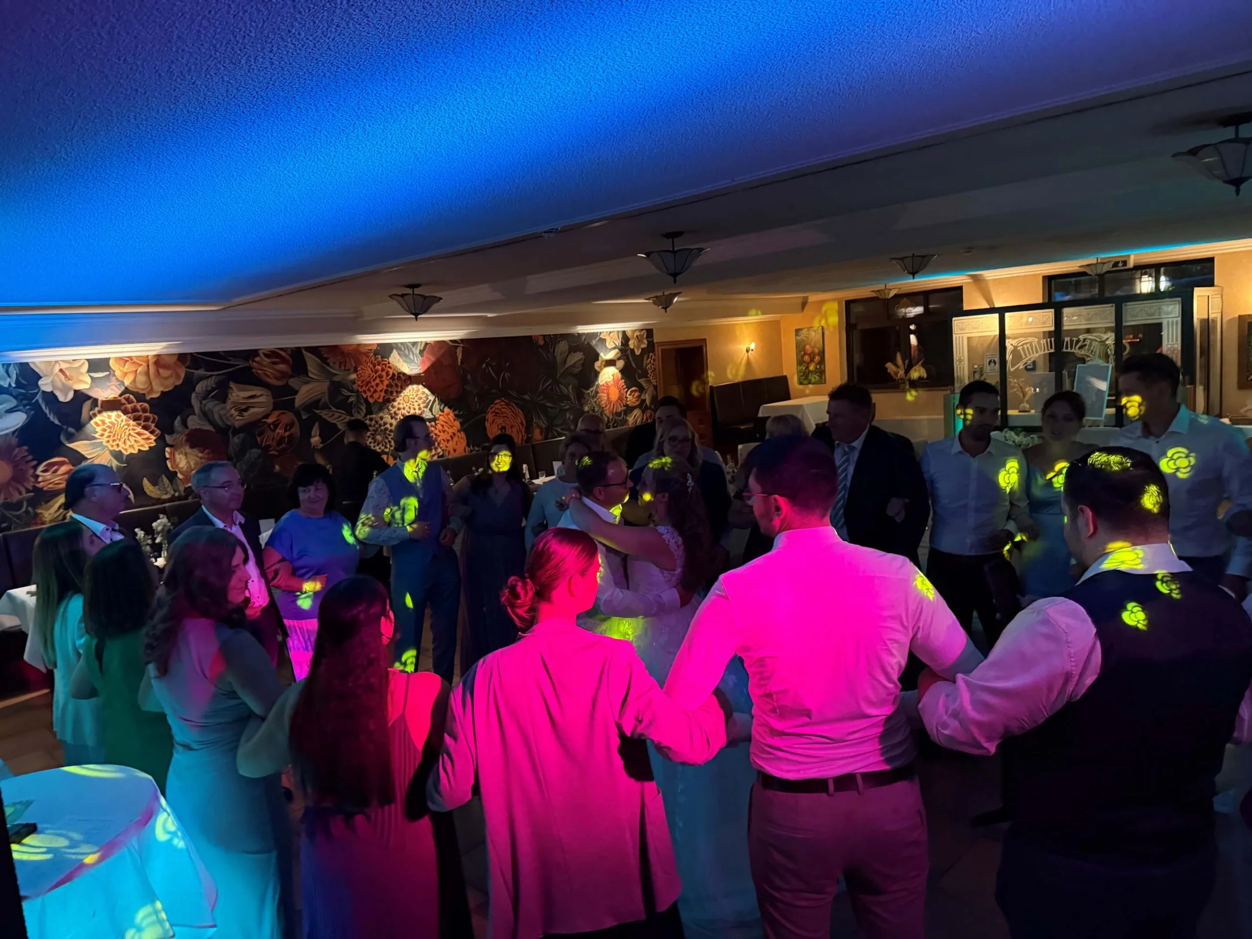 Hochzeitsgäste im Kreis auf der Tanzfläche im Waldhotel Rheinbach mit farbiger Lichtstimmung
